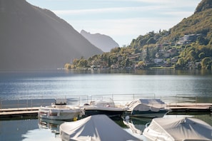 Un lac où sont amarrés des bateaux, une montagne en arrière-plan et une colline parsemée de bâtiments.
