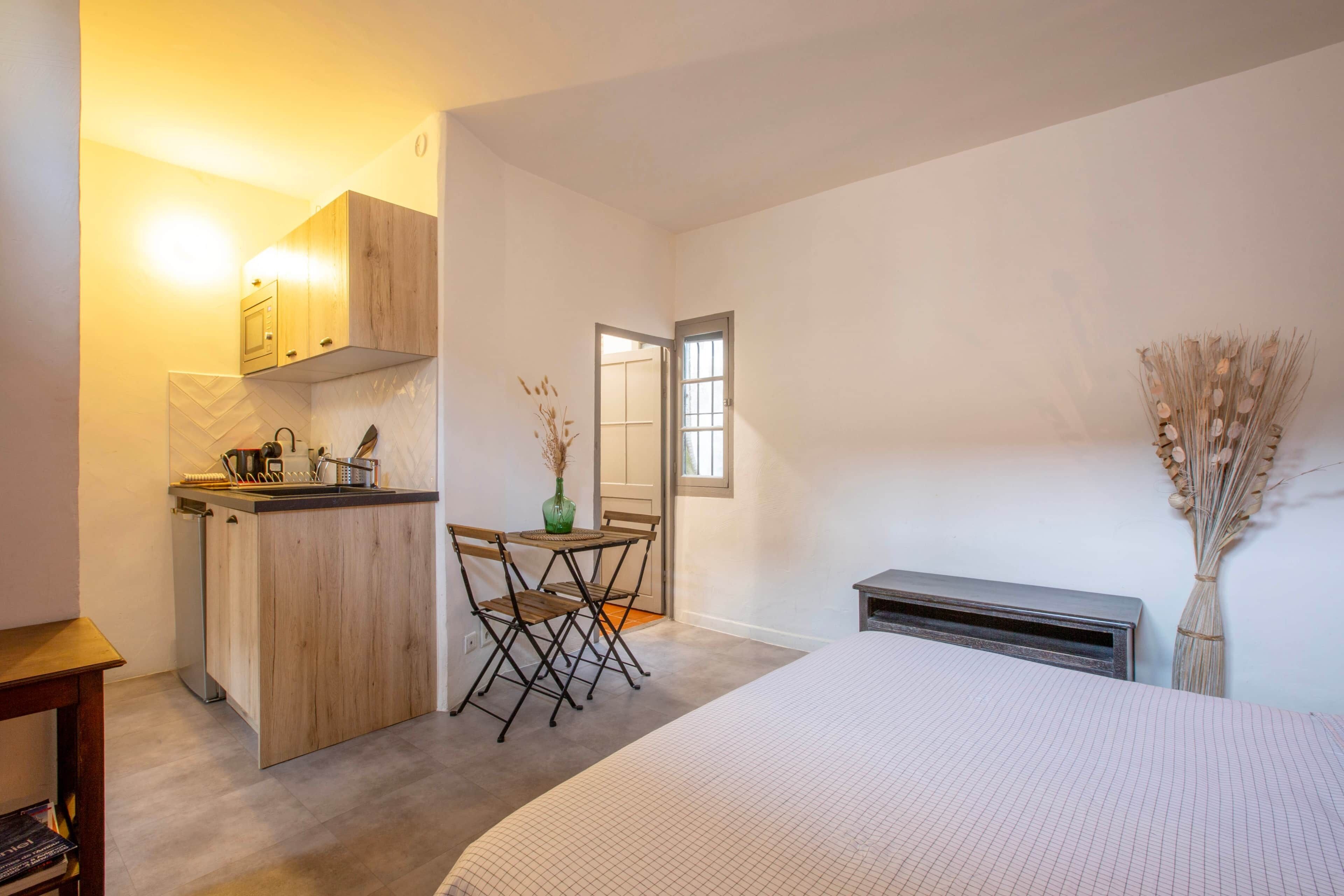 A compact room with a kitchenette, a dining area, and a bed.