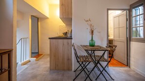 A compact kitchen with a wooden island, a dining table with chairs, and a vase with dried plants. - ✯ RENOVATED ✯ Charming studio Palais des Papes (Avignon)