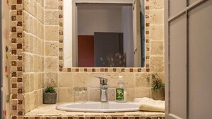 A bathroom with a tiled backsplash, a sink with a mirror above it, a small plant, and a towel on a shelf. - ✯ RENOVATED ✯ Charming studio Palais des Papes (Avignon)