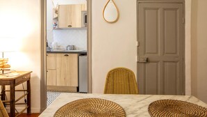 A dining area with a table, chairs, and a kitchen visible through an open door.