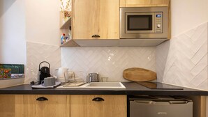 A modern kitchen with wooden cabinets, a stainless steel microwave, a dishwasher, and a herringbone-patterned backsplash.