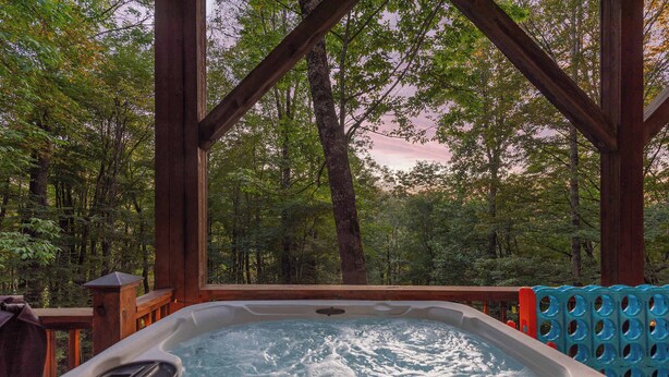 Ein Whirlpool mit einer Holzterrasse und Blick auf einen Wald.