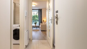 Un couloir d’hôtel avec un lave-linge, un canapé et une vue sur la verdure à l’extérieur.