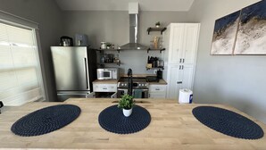 A modern kitchen with a wooden island, stainless steel appliances, and a view of the city. - Cozy Seaside Cottage Escape (Port Bolivar)