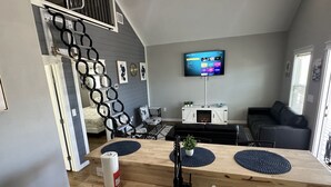 A modern kitchen with a wooden countertop, a built-in sink, and a flat-screen TV mounted on the wall. - Cozy Seaside Cottage Escape (Port Bolivar)