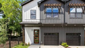 A two-story house with a garage, a front door, and a small porch with wooden railings. - Family Retreat Near NRG Med Center (Houston)