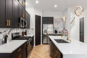 Una cocina moderna con armarios oscuros, electrodomésticos de acero inoxidable y una salpicadura de mármol.