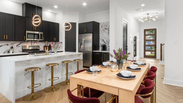 A modern kitchen with dark cabinets, stainless steel appliances, and a marble backsplash. - Family Retreat Near NRG Med Center (Houston)