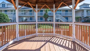 Ein überdachter Außenbereich mit Holzdeck, weißen Geländern und einem Deckenventilator.