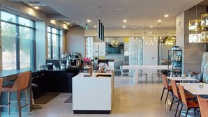 A modern kitchen with a central island, bar seating, and a dining area with tables and chairs. - 2x2 in Medical Center - The Magnolia Resort (Fort Worth)