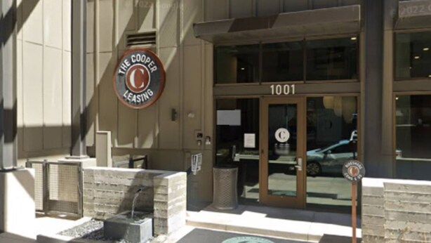 A building entrance with a sign reading "The Cooler" and the number "1001" above the door. - 2x2 in Medical Center - The Magnolia Resort (Fort Worth)