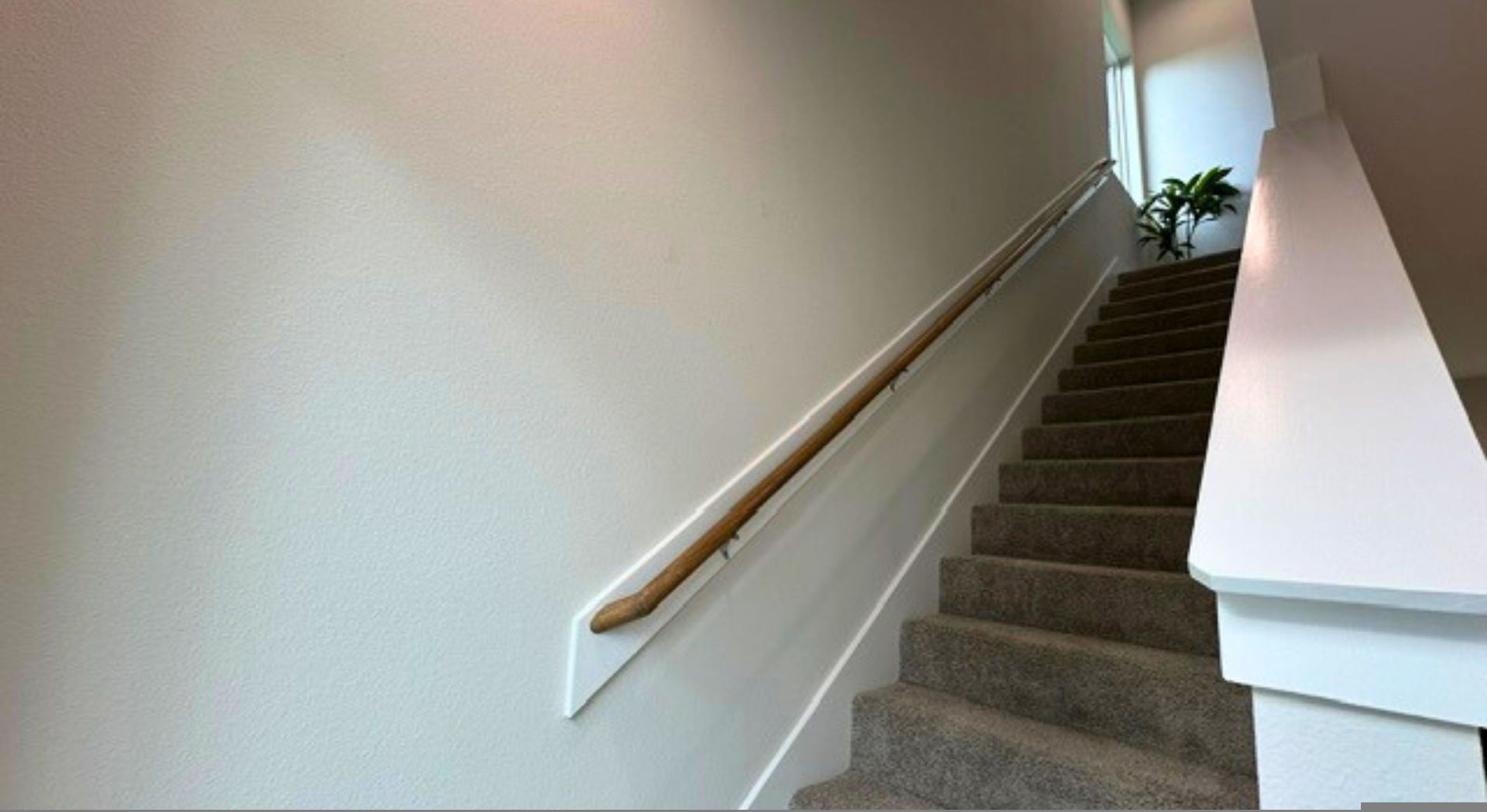 A staircase with a wooden handrail and a white wall.