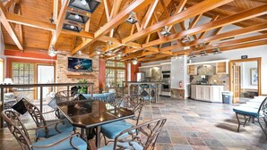 A spacious dining area with a high wooden ceiling, a large table, and blue upholstered chairs. - Upscale 1BR Condo in Med Center (Houston)