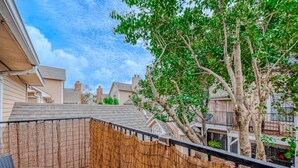 A residential backyard with a wooden fence, a tree, and a chair. - Upscale 1BR Condo in Med Center (Houston)
