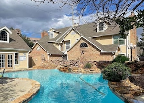 Una propiedad residencial con piscina, muros de piedra y una casa de ladrillo con múltiples chimeneas.