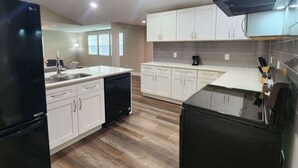 Une cuisine moderne avec des meubles blancs, un réfrigérateur noir et un lave-vaisselle.