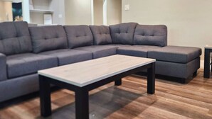 Un salon moderne avec un canapé d’angle, une table basse et un plancher en bois.