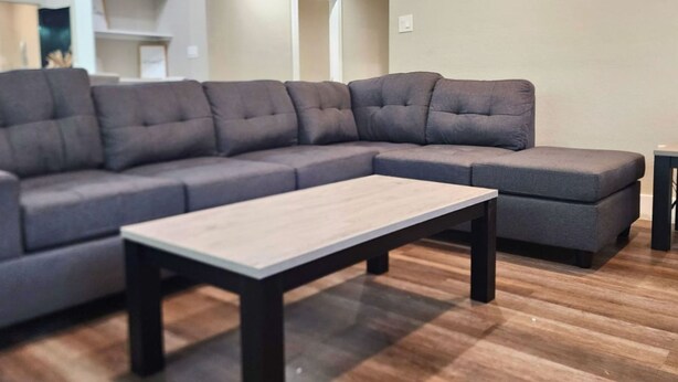 A modern living room with a sectional sofa, a coffee table, and wooden flooring.