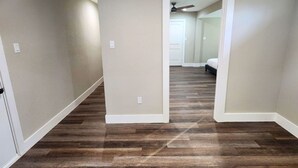A hallway with wooden flooring and white walls.