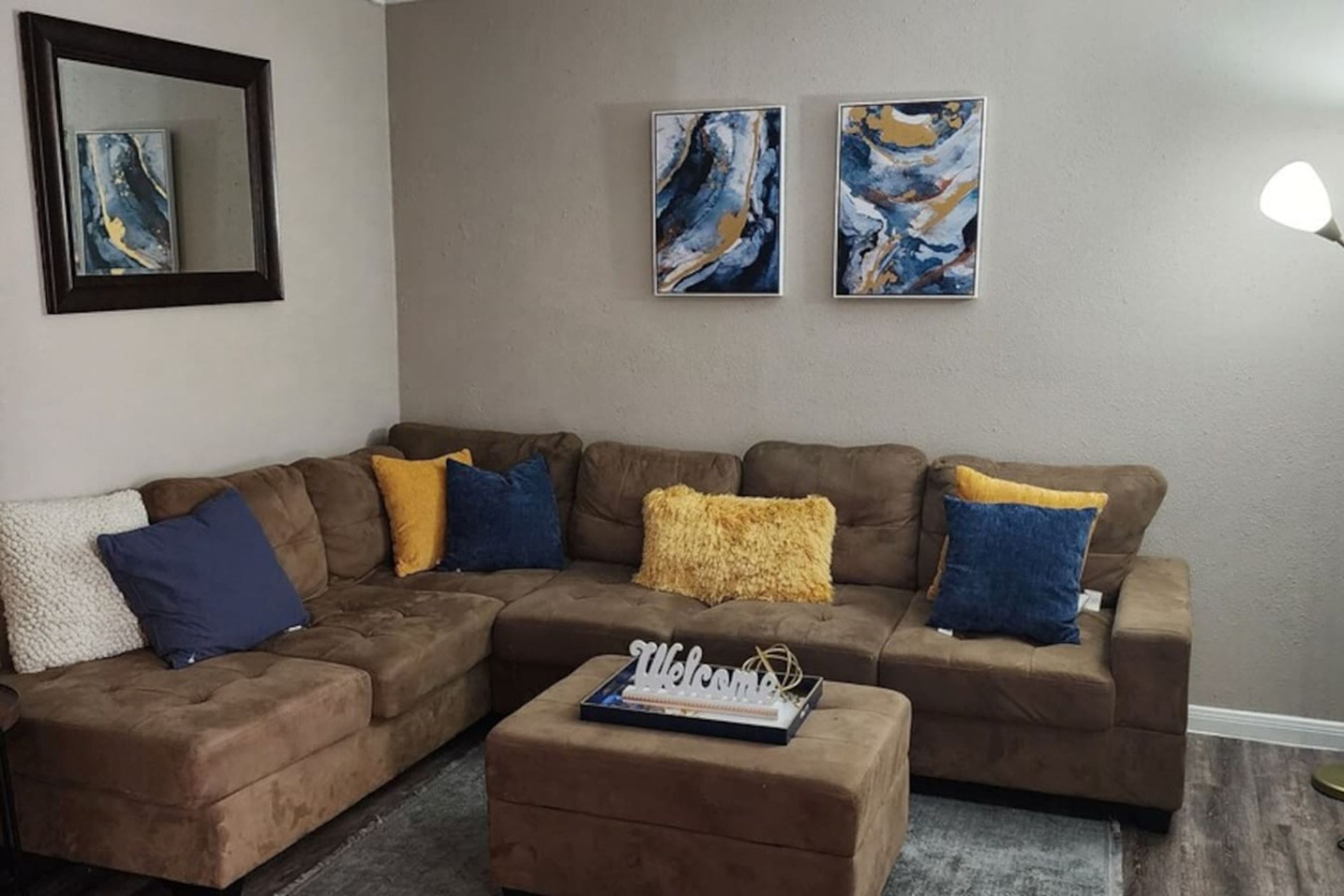 A living room with a sectional sofa, a coffee table, and abstract art on the wall.