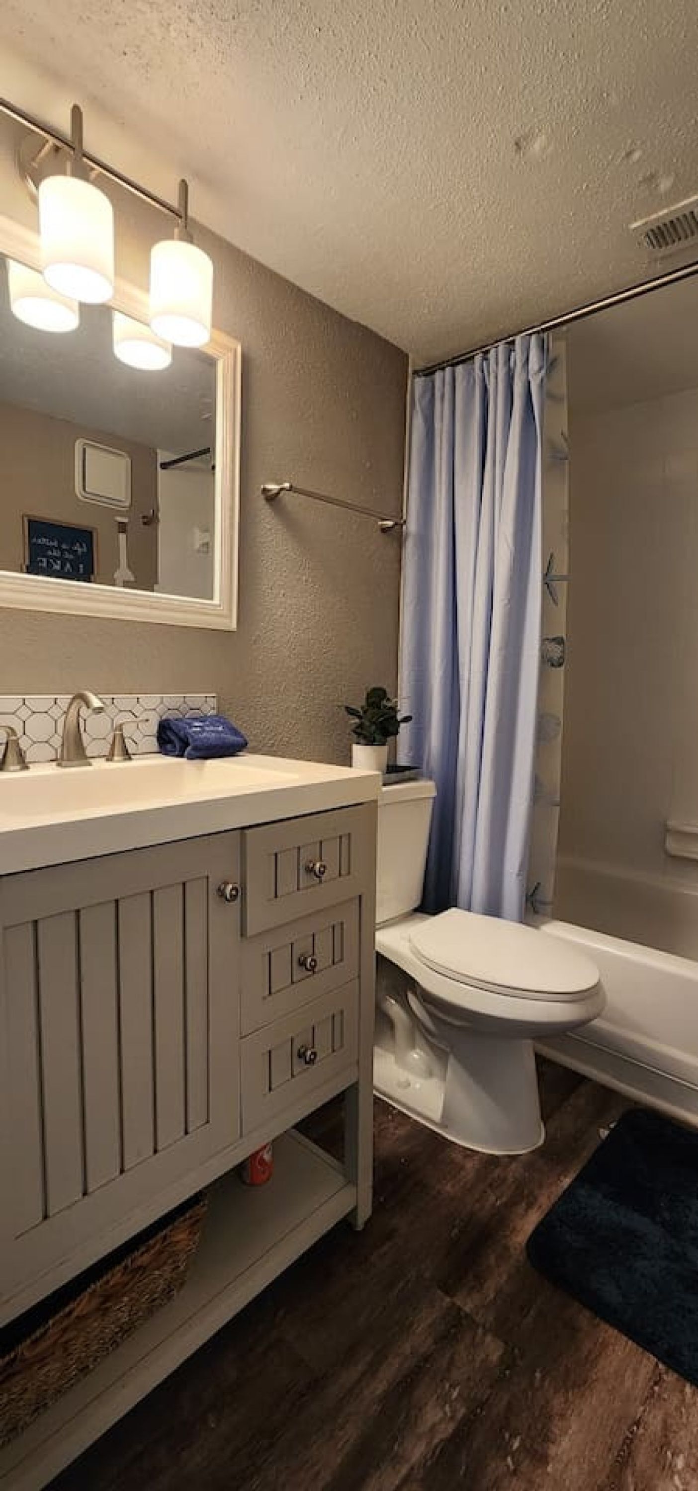 A bathroom with a white vanity, a toilet, and a shower area.