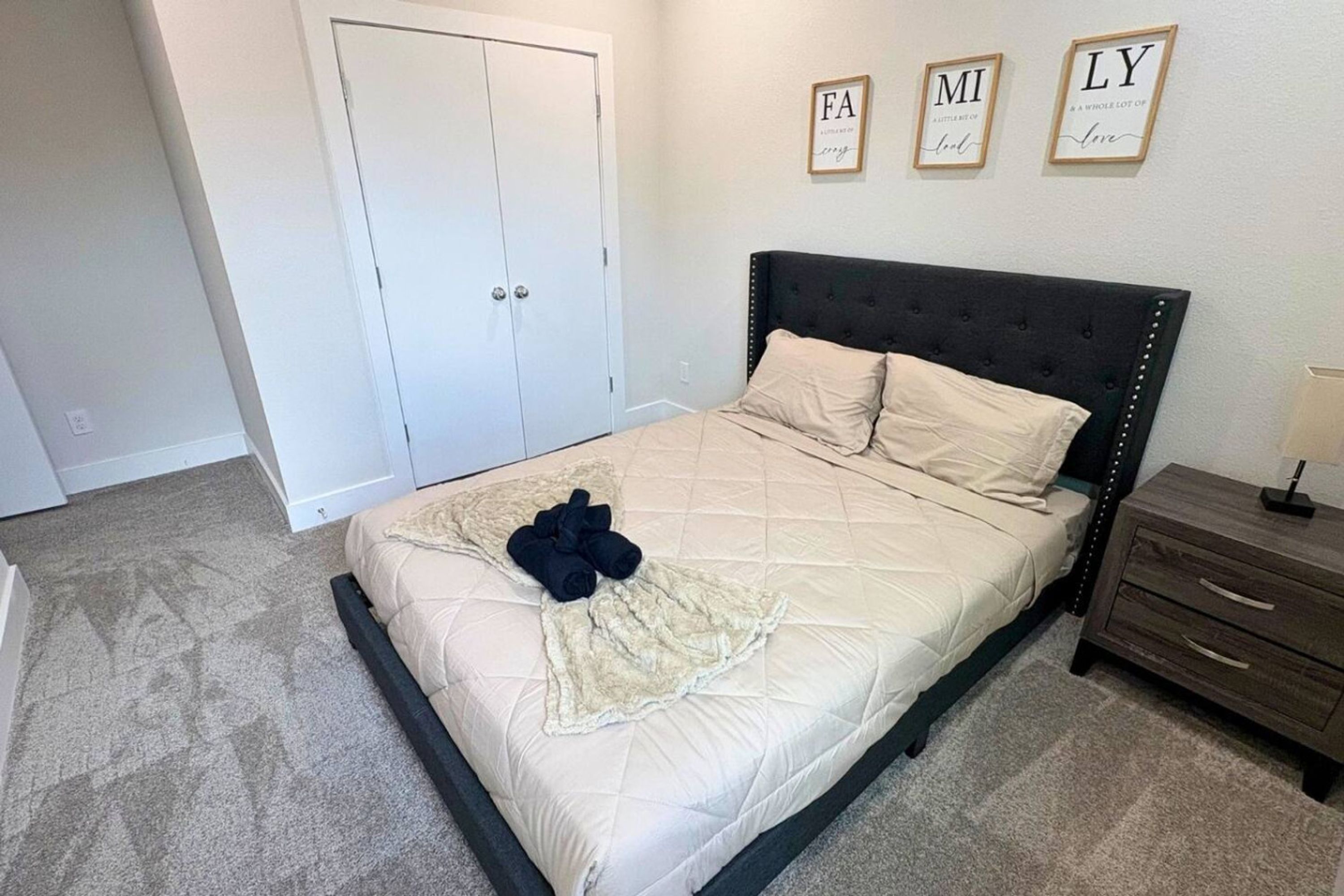 A bedroom with a bed, a nightstand, a dresser, and a door.