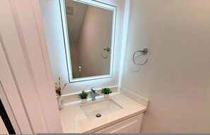 A bathroom with a white sink, a mirror, and two small potted plants on the countertop. - Prebook Fifa With Gated 3BR Near Stadiums (Houston)
