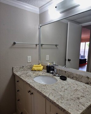 Une salle de bain avec un lavabo doté d’un plan de travail en granit, un miroir et un porte-serviettes.