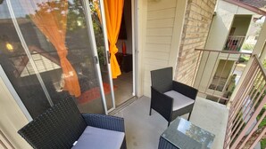 Un balcon doté de meubles en osier, d’une porte vitrée et offrant une vue sur les environs.