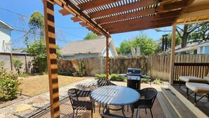 A covered patio with a grill, outdoor furniture, and a wooden deck. - Quiet Heights Hideaway Walk to Restaurants (Houston)