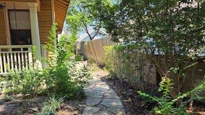 A stone pathway leading to a house with a porch, surrounded by lush greenery and a fence. - Quiet Heights Hideaway Walk to Restaurants (Houston)
