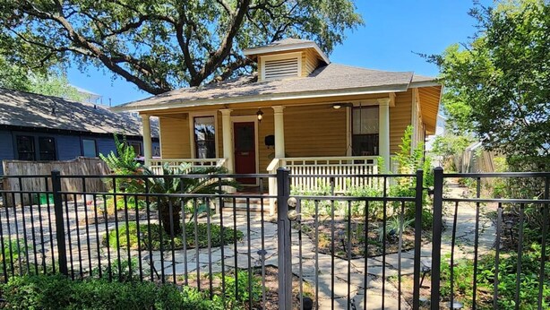 A single-story house with a front porch, a small front yard, and a black metal fence. - Quiet Heights Hideaway Walk to Restaurants (Houston)