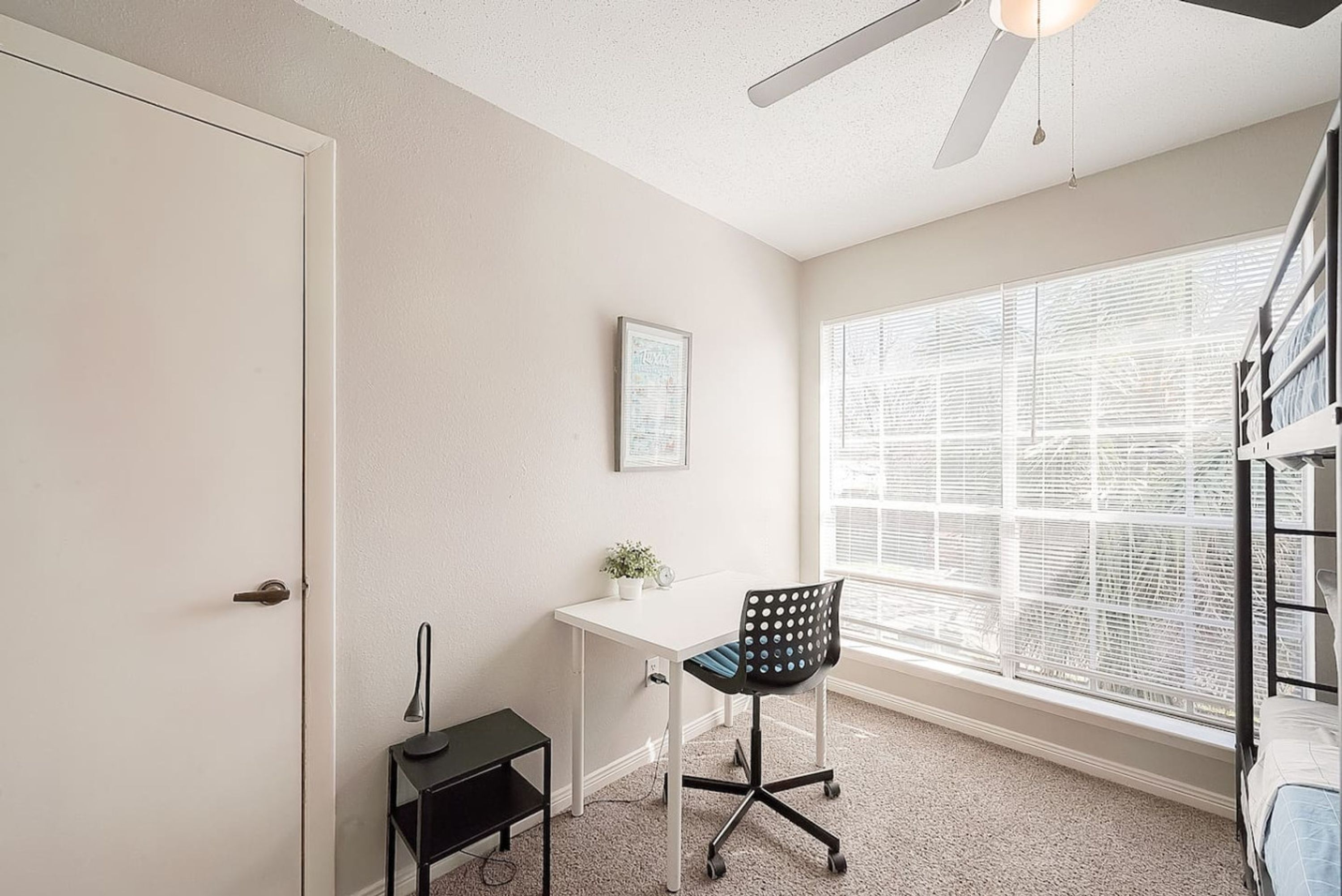 A compact room with a desk, chair, and a window with blinds.