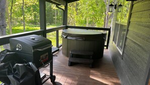 A covered outdoor area with a grill, a hot tub, and a wooden deck. - Mountain Cabin Getaway Jacuzzi Stunning Views (Sevierville)