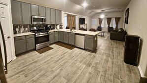 A spacious kitchen with grey cabinets, a stainless steel stove, and a large island. - Serenity in Suburbia - Katy Tx (Katy)