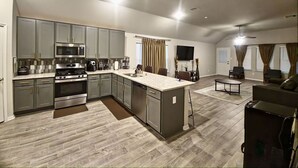 A modern kitchen with grey cabinets, stainless steel appliances, and a large island. - Serenity in Suburbia - Katy Tx (Katy)