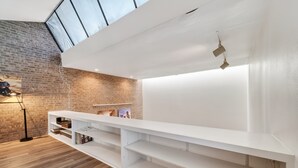 A modern interior with exposed brick walls, a white built-in shelf, and a skylight. - Private Pool Oasis Montrose Retreat Sleeps 8 (Houston)