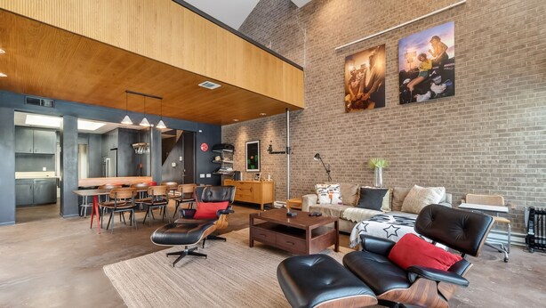 A modern living room with a dining area, featuring a brick wall, wooden ceiling, and contemporary furniture. - Private Pool Oasis Montrose Retreat Sleeps 8 (Houston)
