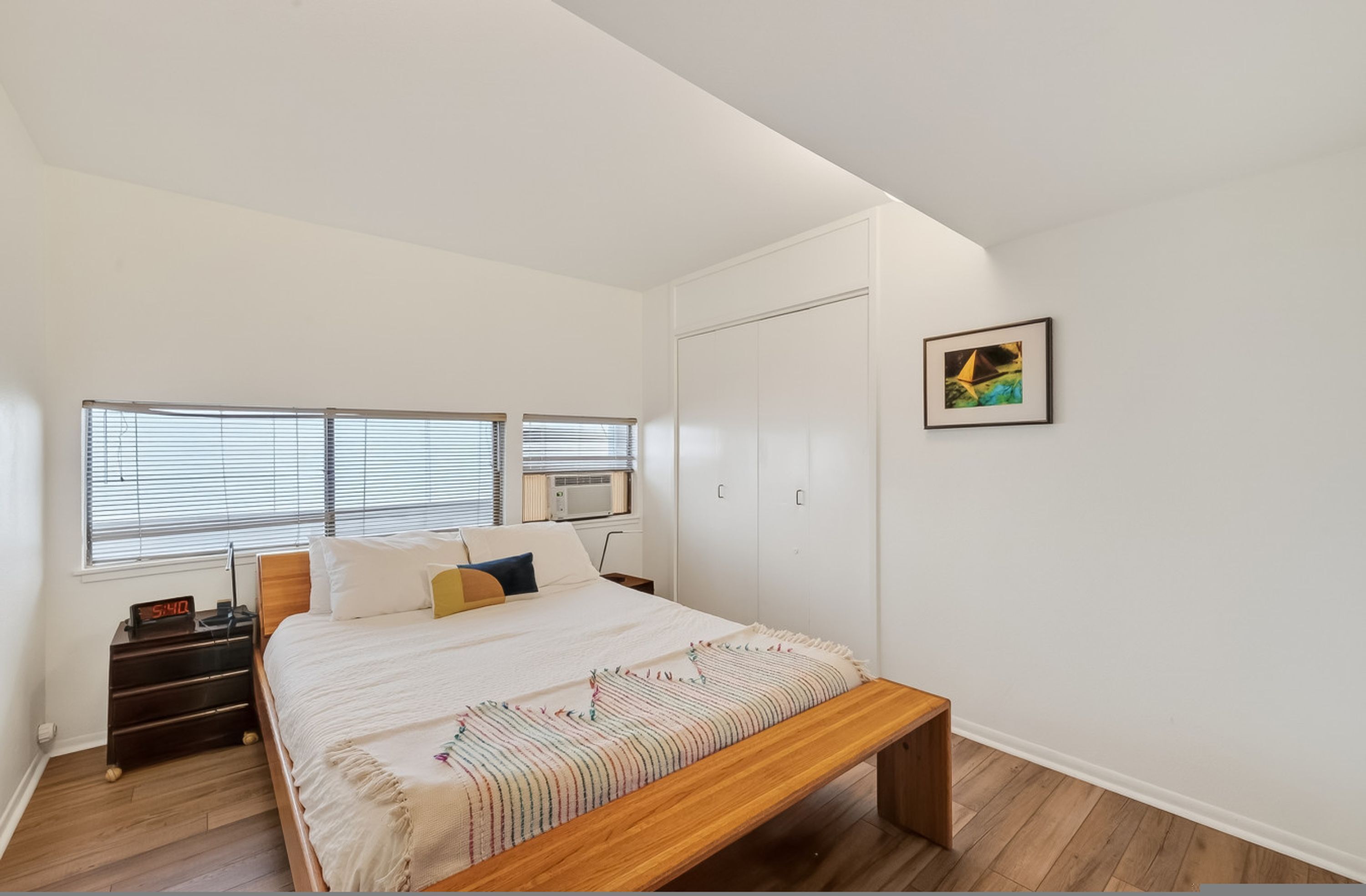 Un dormitorio con cama, mesita de noche y ventana.