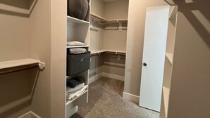 Um closet espaçoso com prateleiras, porta e piso coberto por carpete.