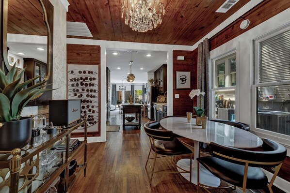 A modern kitchen with wooden accents, a dining area with a round table and chairs, and a chandelier.