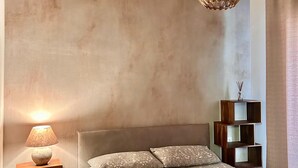 Een slaapkamer met een bed, een bedlamp, een hanglamp en een houten plank.