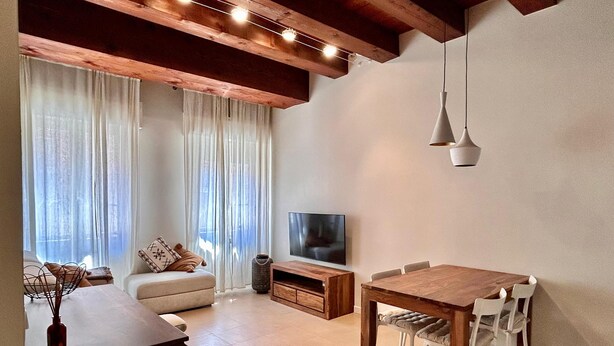 Een moderne woonkamer met een bank, televisie, eettafel en stoelen.