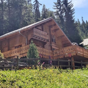 A wooden chalet with a balcony, surrounded by greenery and trees. - 'Bas De Lout'Chi Valfréjus' Apartment with Mountain View, Private Terrace and Wi-Fi (Valfréjus)