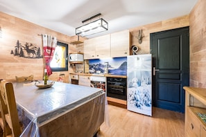 Una cocina con armarios de madera, un refrigerador y una mesa de comedor cubierta con plástico.