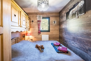 Una habitación de madera con una cama, un ventanal, una lámpara y un perro.