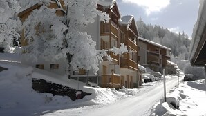 A snow-covered building with multiple balconies, a clear sky, and a snow-covered road. - Apartment 'Chalet Refuge Loup Blanc Valfréjus' with Mountain View, Balcony and Wi-Fi (Valfréjus)