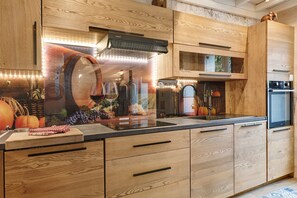 Una cocina con muebles de madera, horno empotrado y una estantería para vinos.