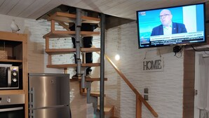 Una cocina moderna con horno empotrado, refrigerador de acero inoxidable y escalera de madera.